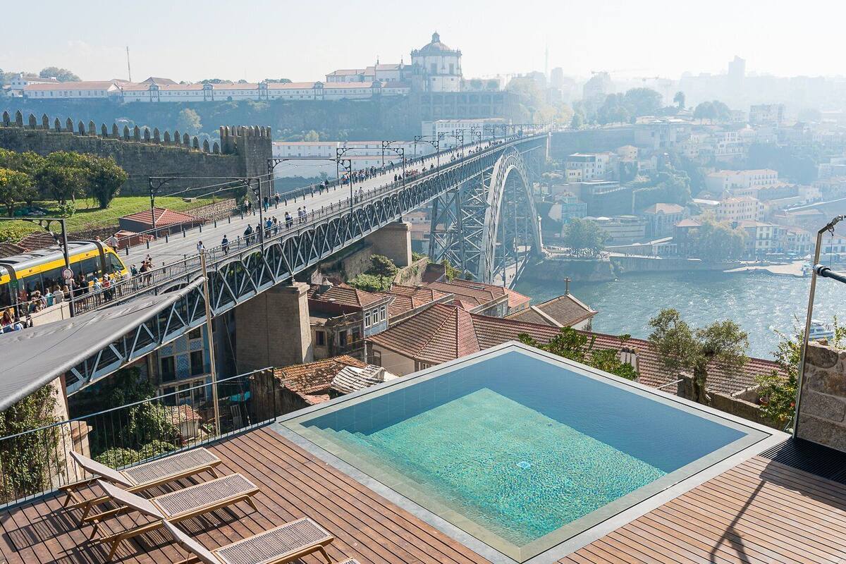 A view of a bridge over a river with a swimming pool in the foreground.