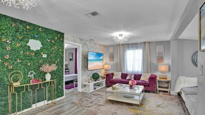 A modern living room with a green wall, a purple sofa, and a white coffee table. - Charming 3-bedroom home with hot pool and spa. (Clearwater)