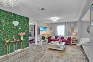 Ein modernes Wohnzimmer mit grüner Wand, einem violetten Sofa und einem weißen Couchtisch.