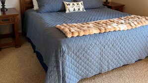 A bedroom with a bed, two nightstands, a ceiling fan, and a wall-mounted lamp. - The Good Life - Okoboji cabin in Bridges Bay (Arnolds Park)