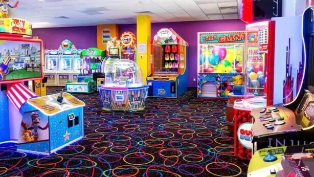 An arcade with various games and a floor covered with colorful rings. - The Good Life - Okoboji cabin in Bridges Bay (Arnolds Park)