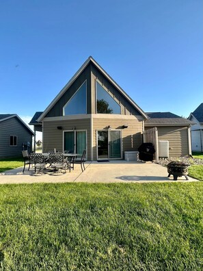 Une maison moderne à deux étages dotée d’un patio, d’un espace salon extérieur et d’un foyer.