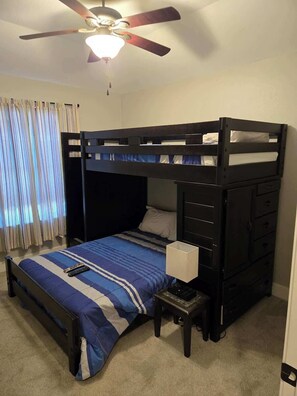 A bunk bed with a desk and chair, a ceiling fan, and a window with curtains. - Movie Room | Huge Patio|Hot Tub|Near Lake & Frisco (Little Elm)