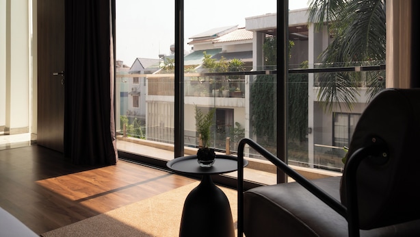 Una habitación moderna con un gran ventanal, una mesita redonda y una silla.