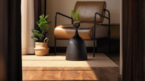 Una habitación moderna con un sillón de cuero, una lámpara de pie y una planta en maceta.