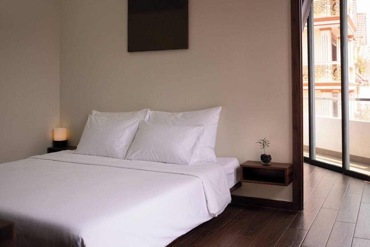 Een net opgemaakt bed met witte lakens in een hotelkamer.