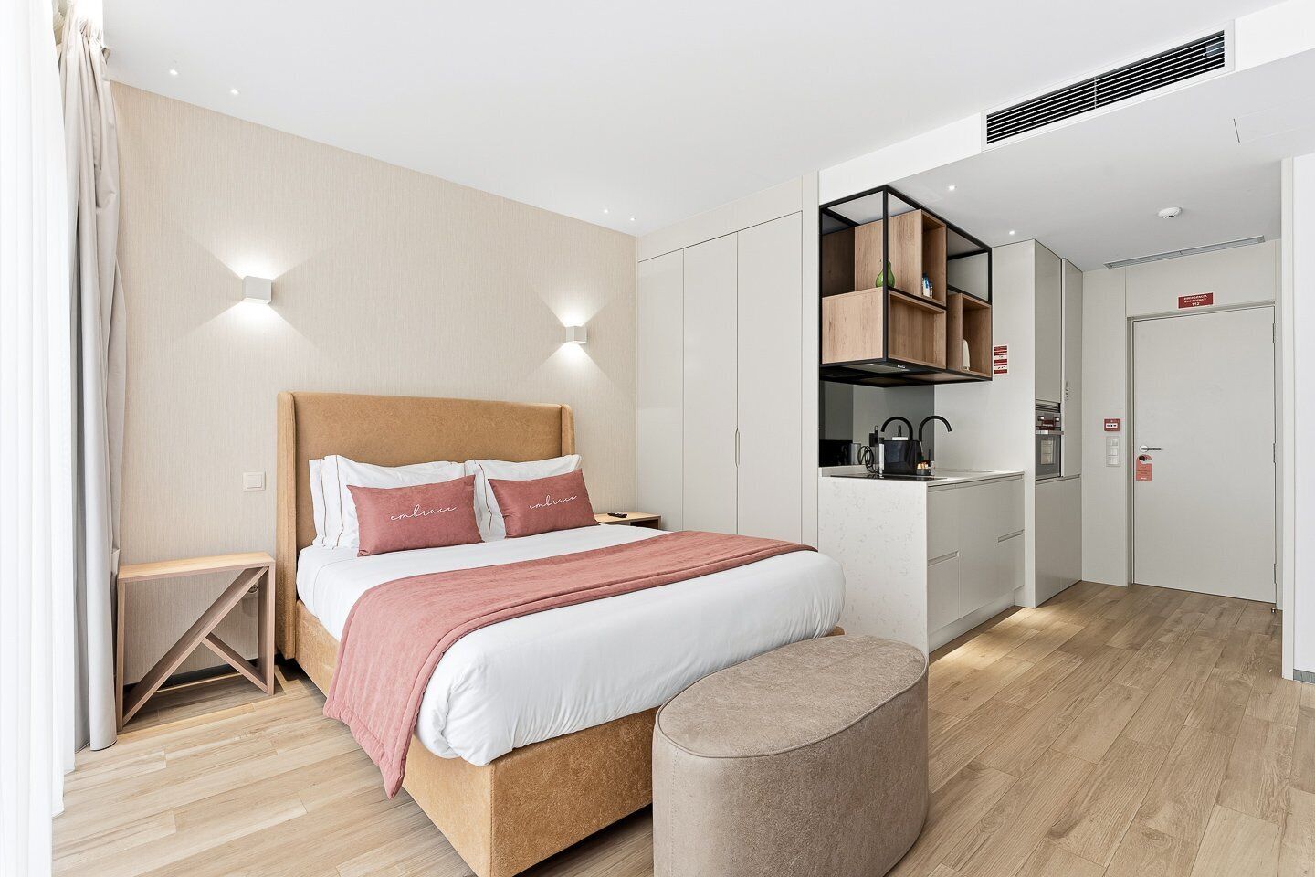 Een moderne slaapkamer met een houten bed, nachtkastjes, een inbouwkast en een kitchenette.