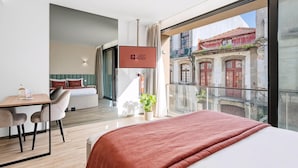A modern hotel room with a balcony, a bed, a desk, and a TV displaying 'GUEST READY'. - Guestready - Alma Invicta (Porto)