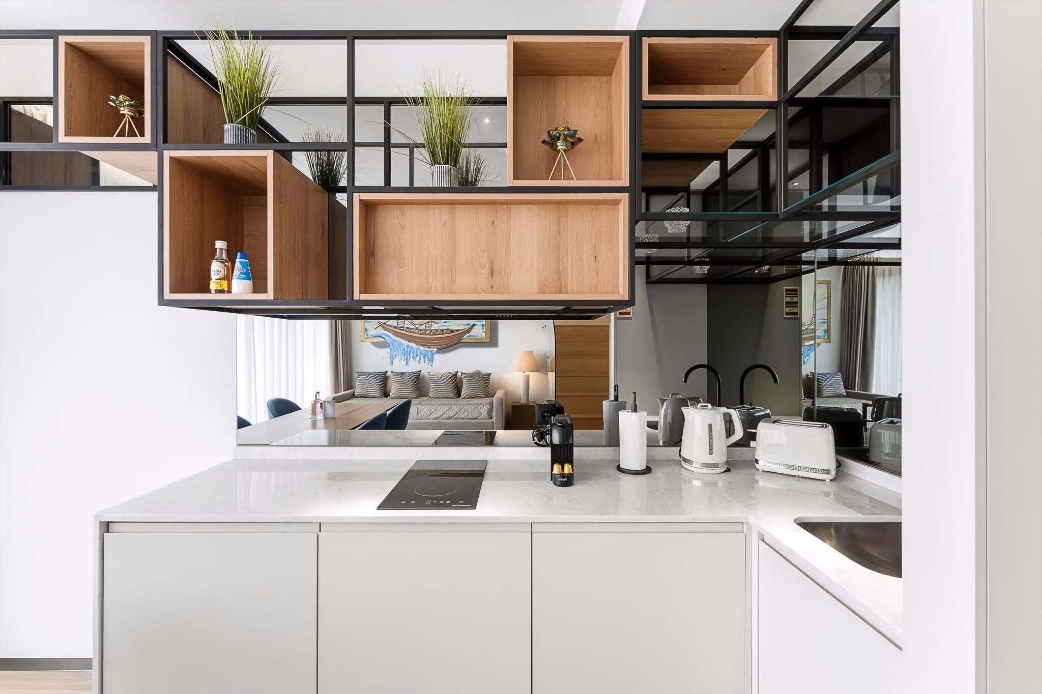A modern kitchen with built-in appliances, a central island, and a dining area with a view of the living room.
