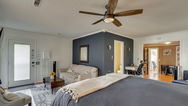 Une chambre à coucher comprenant un lit, un ventilateur de plafond, un canapé, un bureau et une chaise.
