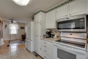 Eine Küche mit weißen Schränken, einer Mikrowelle, einem Backofen und einem Kühlschrank.