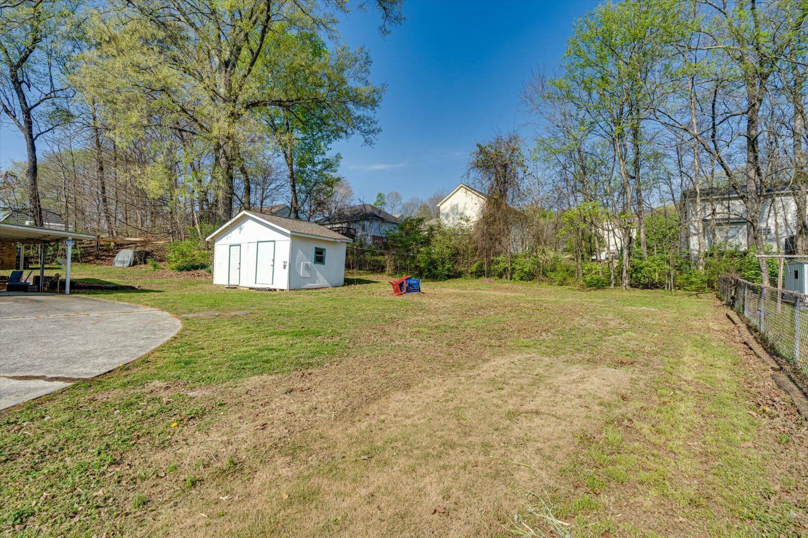 A residential property with a detached house, a small shed, and a fenced yard.