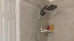 Kylpyhuone, jossa on kylpyamme, suihku ja hylly, jossa on hygieniatuotteita.