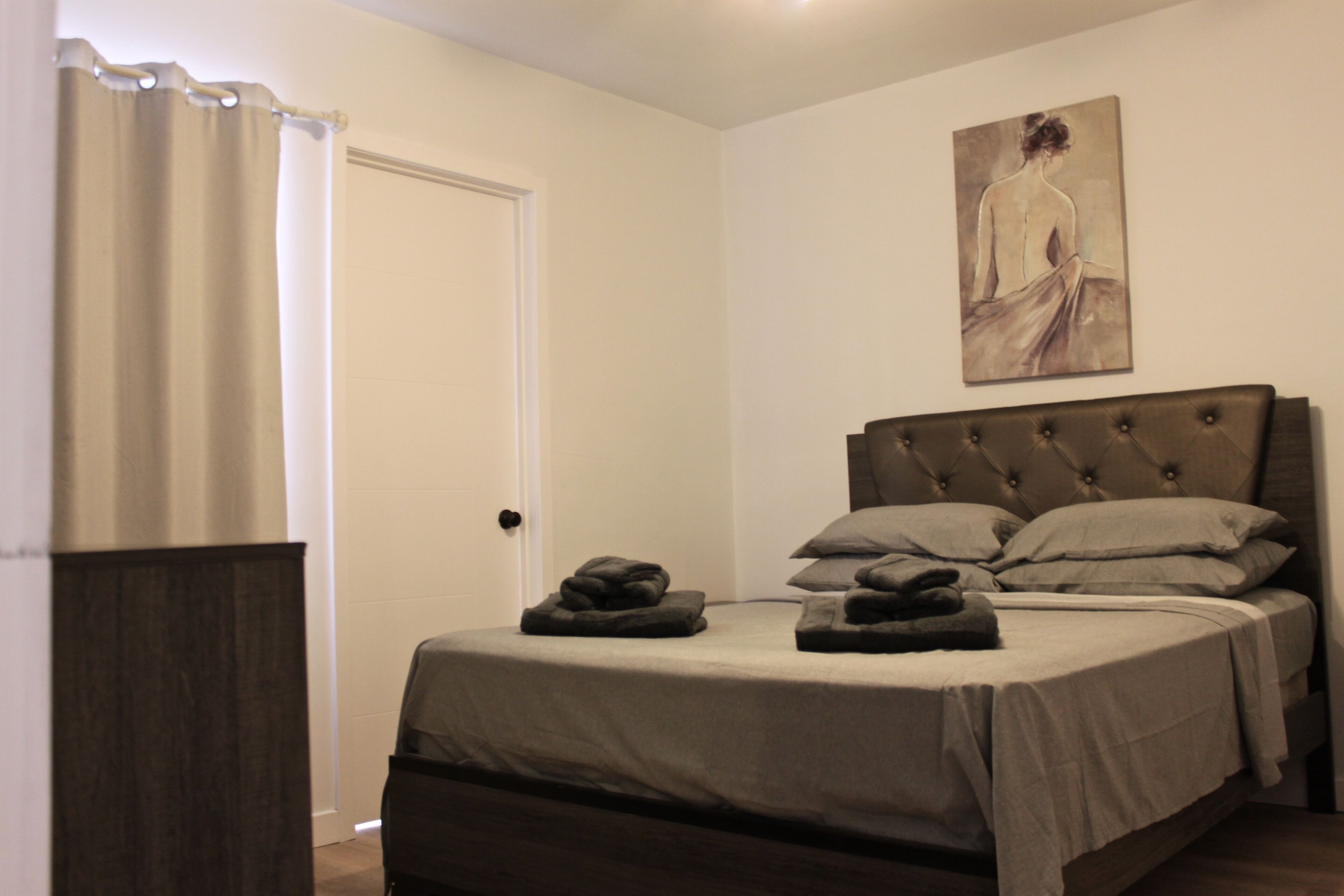 A bedroom with a bed, a door, and a painting on the wall.
