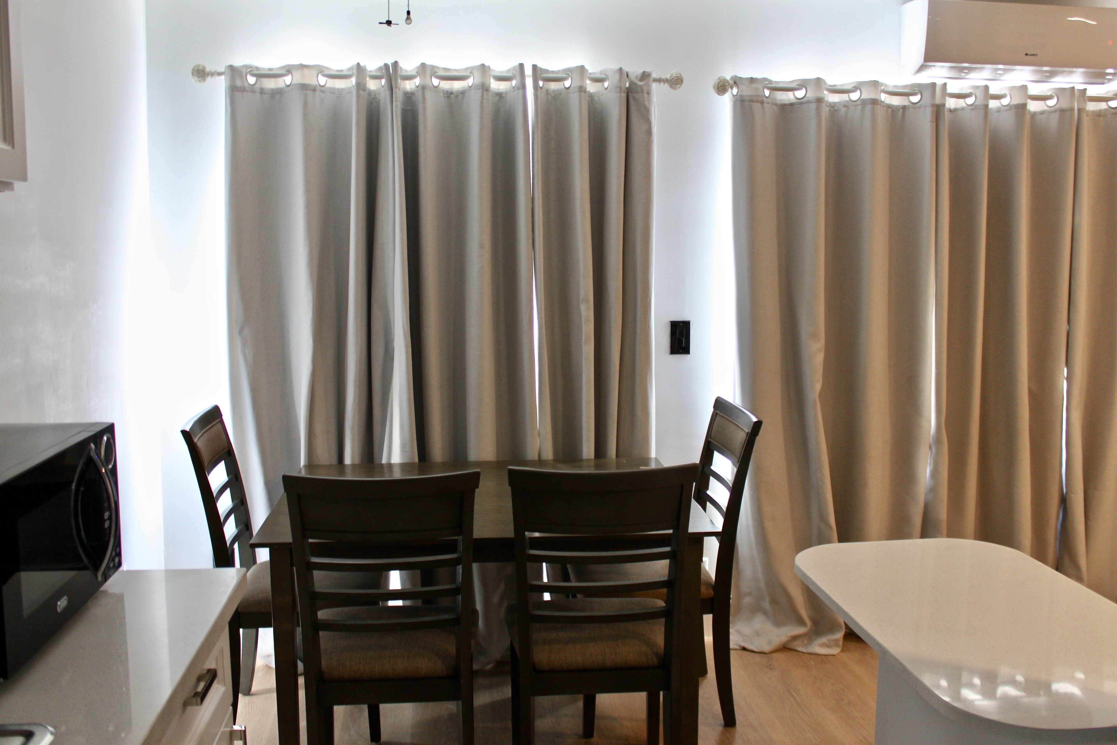 A dining area with a table and chairs, a microwave, and curtains.