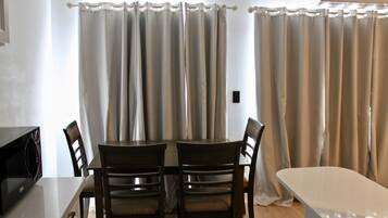 A dining area with a table and chairs, a microwave, and curtains.