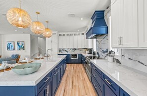 Cozinha moderna com armários azuis, bancada de mármore e uma ilha central.