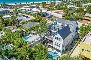 A multi-story hotel with a pool, surrounded by lush greenery and a beach view. - Stunning Home w/ Pool, Slide & Spa & Rooftop Views! (Sarasota)