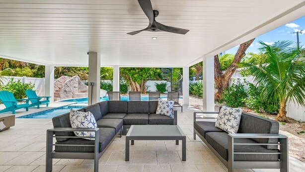 Un patio exterior con piscina, ventilador de techo y mobiliario.