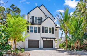 A two-story house with a garage, surrounded by tropical vegetation. - Stunning Home w/ Pool, Slide & Spa & Rooftop Views (Sarasota)