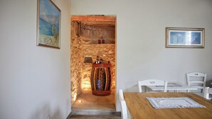 Una habitación con pared de piedra, un barril de madera, una mesa y sillas.
