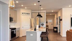 A modern kitchen with a central island, stainless steel appliances, and pendant lighting. - Spacious Retreat w/ King Suite, 3 Baths + Yard (Graham)