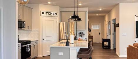 A modern kitchen with a central island, stainless steel appliances, and pendant lighting.