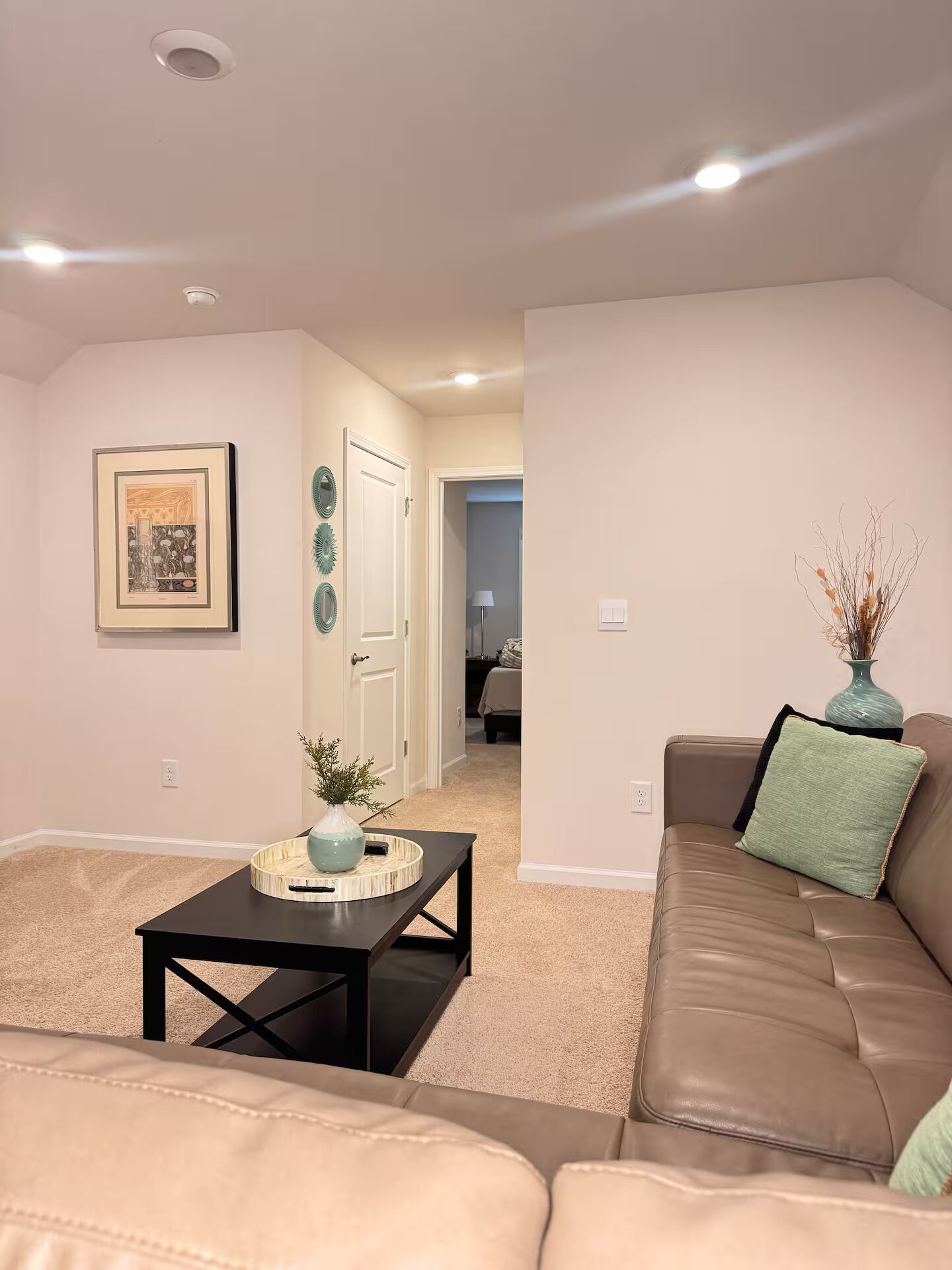 A living room with a brown leather sofa, a black coffee table, and a framed picture on the wall.