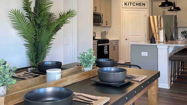 A modern kitchen with hanging light fixtures, a central island with bowls, and a 'KITCHEN' sign. - Spacious Retreat w/ King Suite, 3 Baths + Yard (Graham)