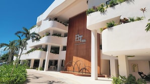 Un hôtel moderne doté de nombreux balcons, d’une entrée imposante et de plantes d’extérieur.