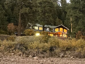 Et moderne hus i to etager med store vinduer, omgivet af tæt skov.