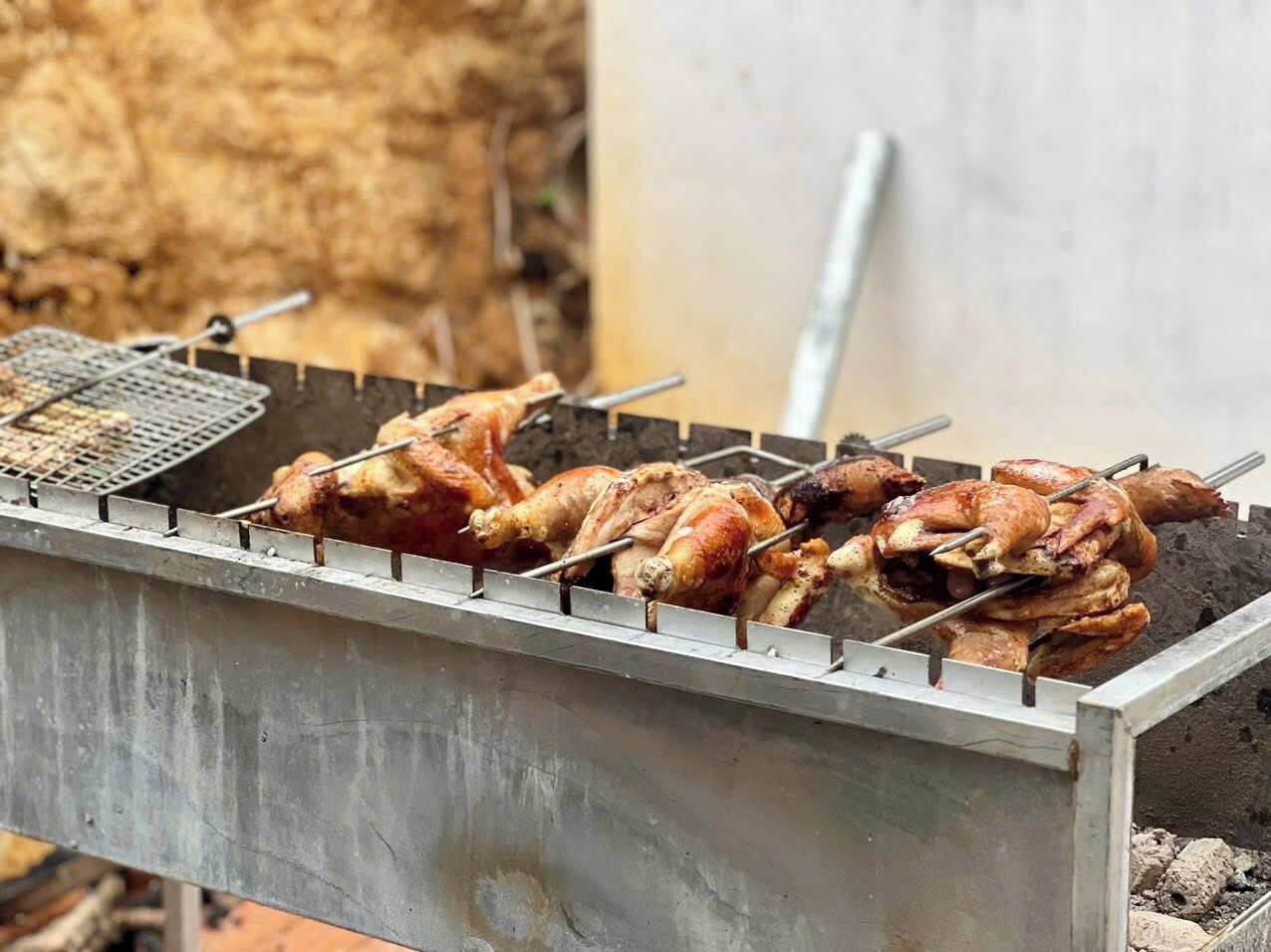 A metal grill with several whole chickens being cooked.