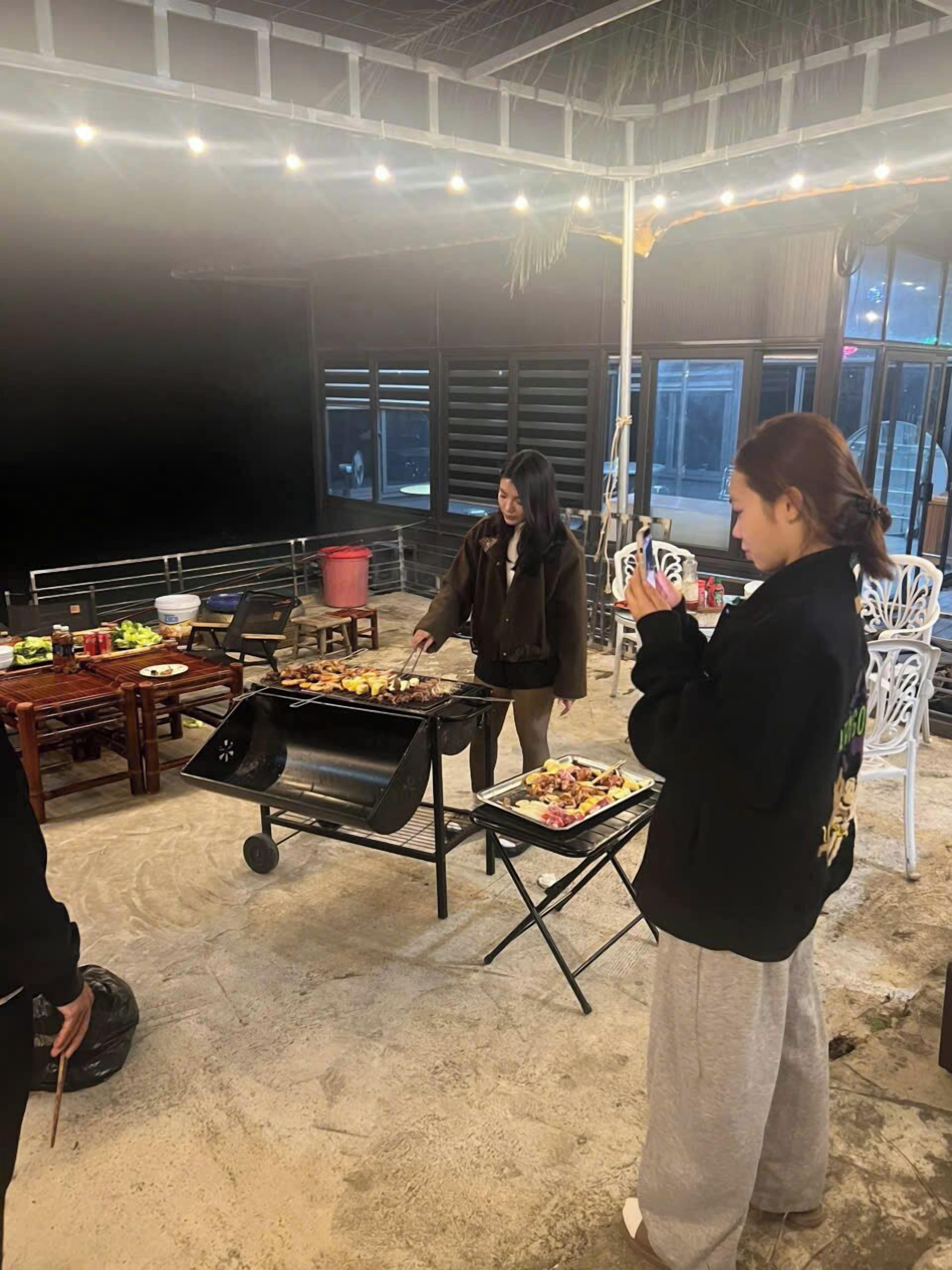 Un evento al chiuso con una griglia per barbecue, tavoli imbanditi di cibo e persone.