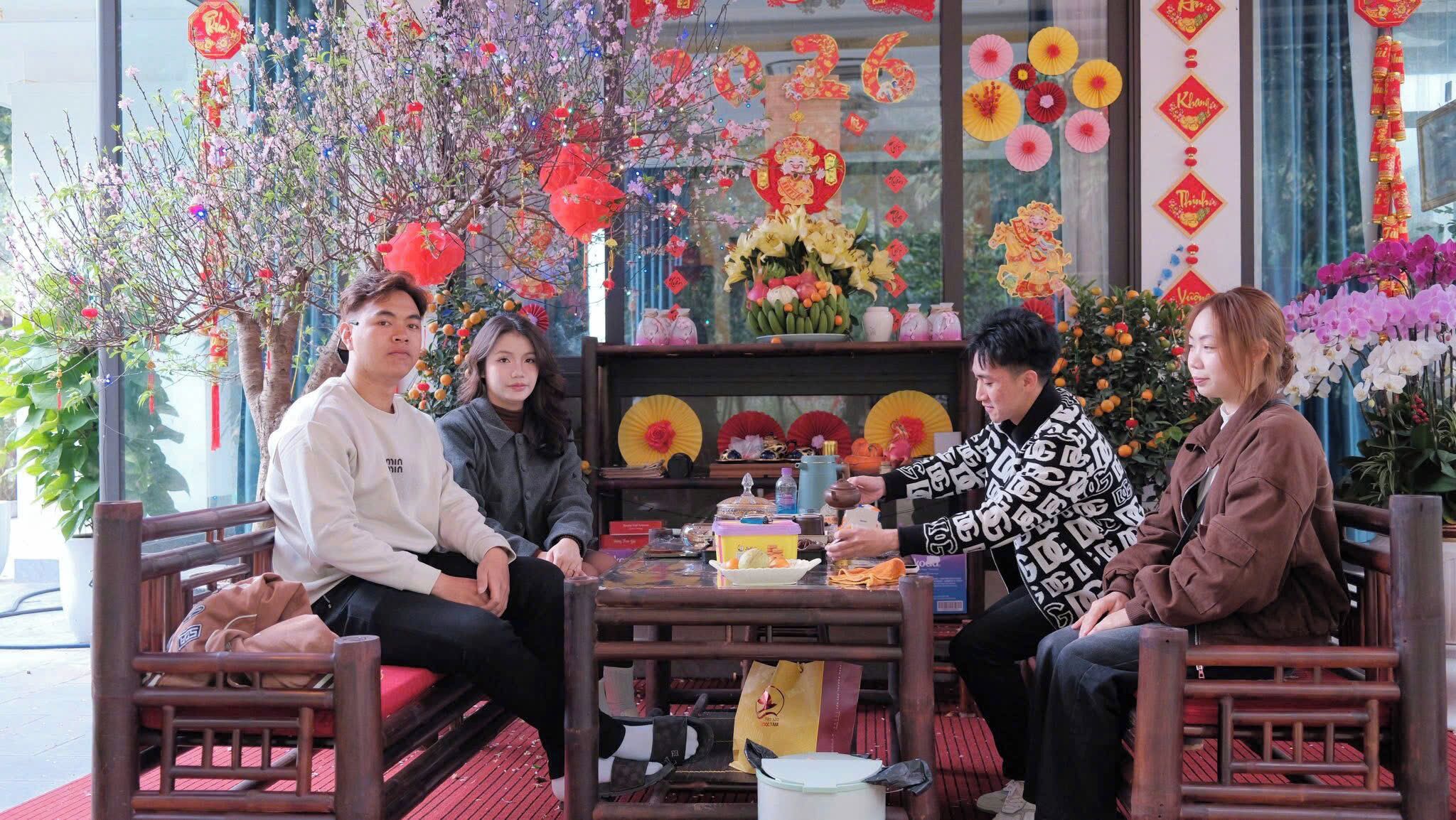 A group of people seated at a table with traditional decorations and flowers, indicating a cultural or festive setting.