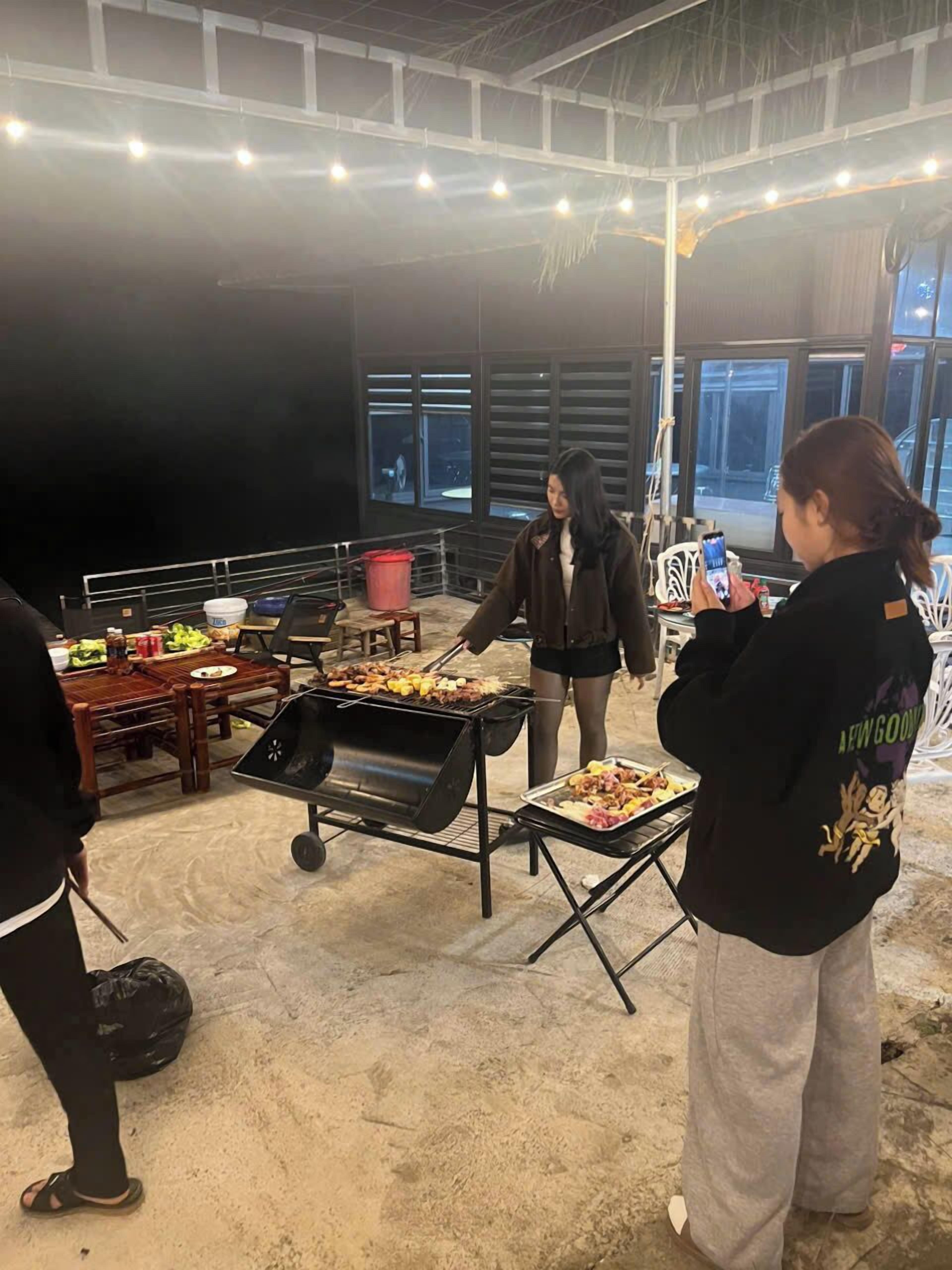 An indoor event with a grill, tables, and people.