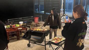 An indoor event with a grill, tables, and people.