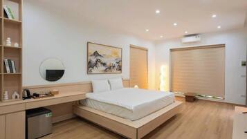 A modern bedroom with a bed, bedside table, bookshelf, and artwork.