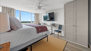 Un dormitorio con cama, escritorio, silla, televisor y armario.