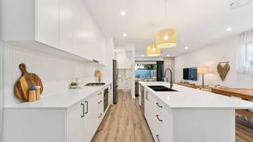 A modern kitchen with white cabinetry, a central island, and a dining area with a wooden table.