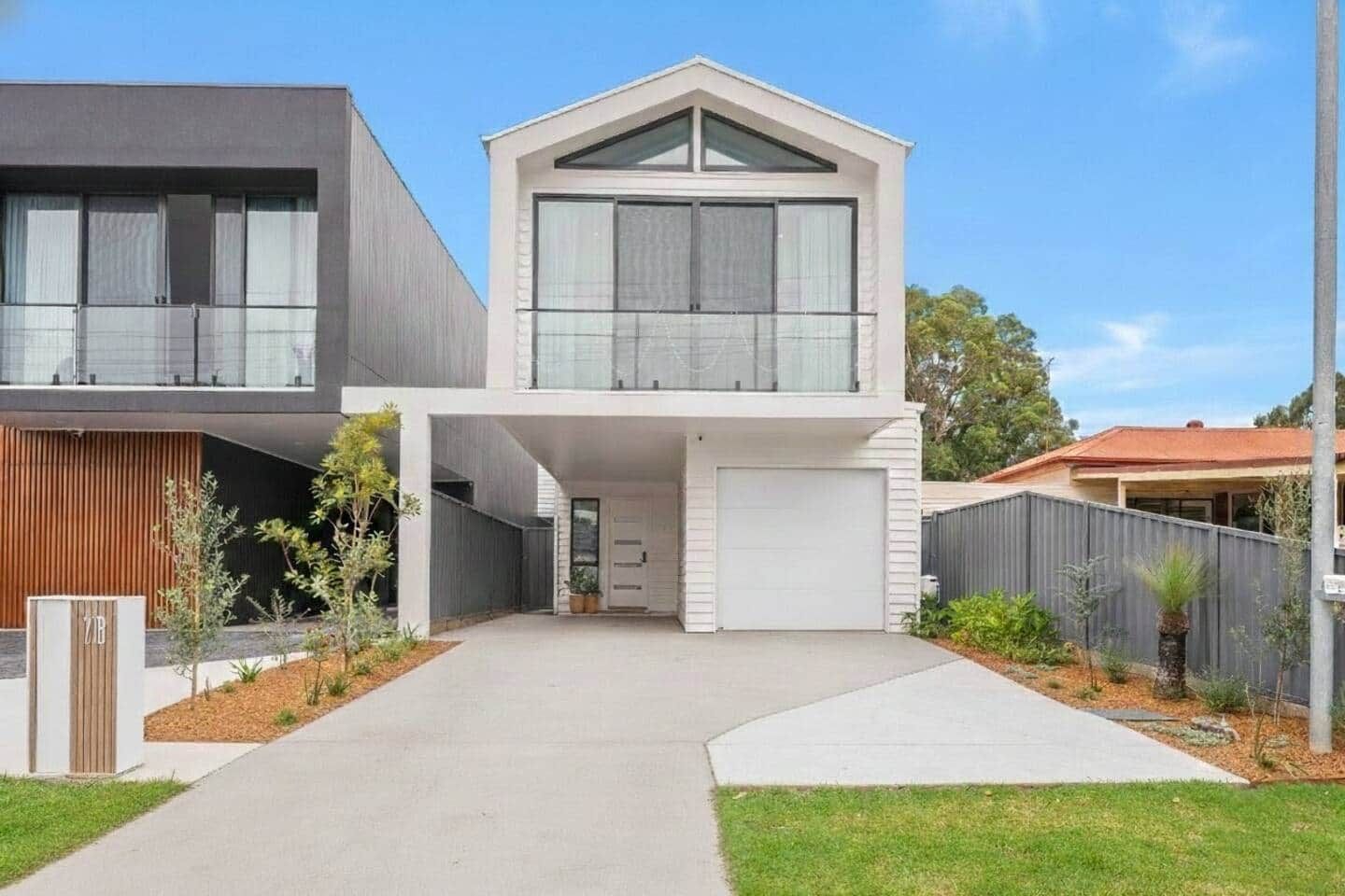 A modern two-story house with a garage, a covered driveway, and a fenced yard.