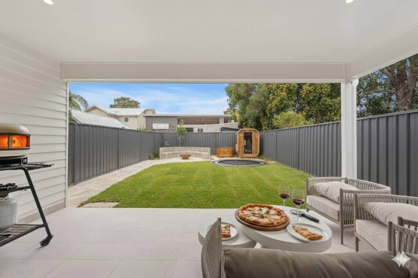 A backyard patio with a dining table, chairs, and a pizza.