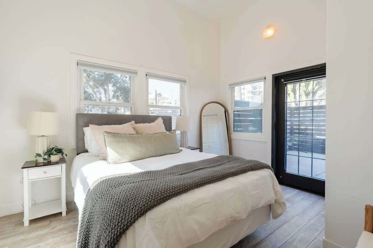 A bedroom with a bed, bedside tables, a mirror, and a window.