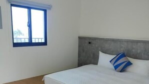 Un dormitorio con cama, ventana y mesita de noche con una caja de pañuelos.