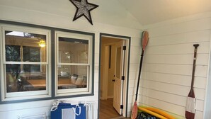 Una habitación con decoración de estrellas, una ventana con vistas, una silla plegable azul y tablas de remo apoyadas contra la pared.