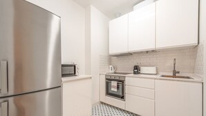 A modern kitchen with stainless steel appliances, white cabinetry, and patterned floor tiles. - Guestready - Urban Garden Apartments (Lisbon)