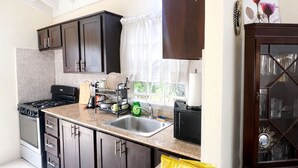 A kitchen with dark wooden cabinets, a granite countertop, a stove, and a microwave. - RHE Drax Hall Ocho Rios Gated/Pool/Gym (Saint Ann's Bay)