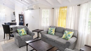 A spacious living room with a high ceiling, grey sofas, a coffee table, and a ceiling fan. - RHE Drax Hall Ocho Rios Gated/Pool/Gym (Saint Ann's Bay)