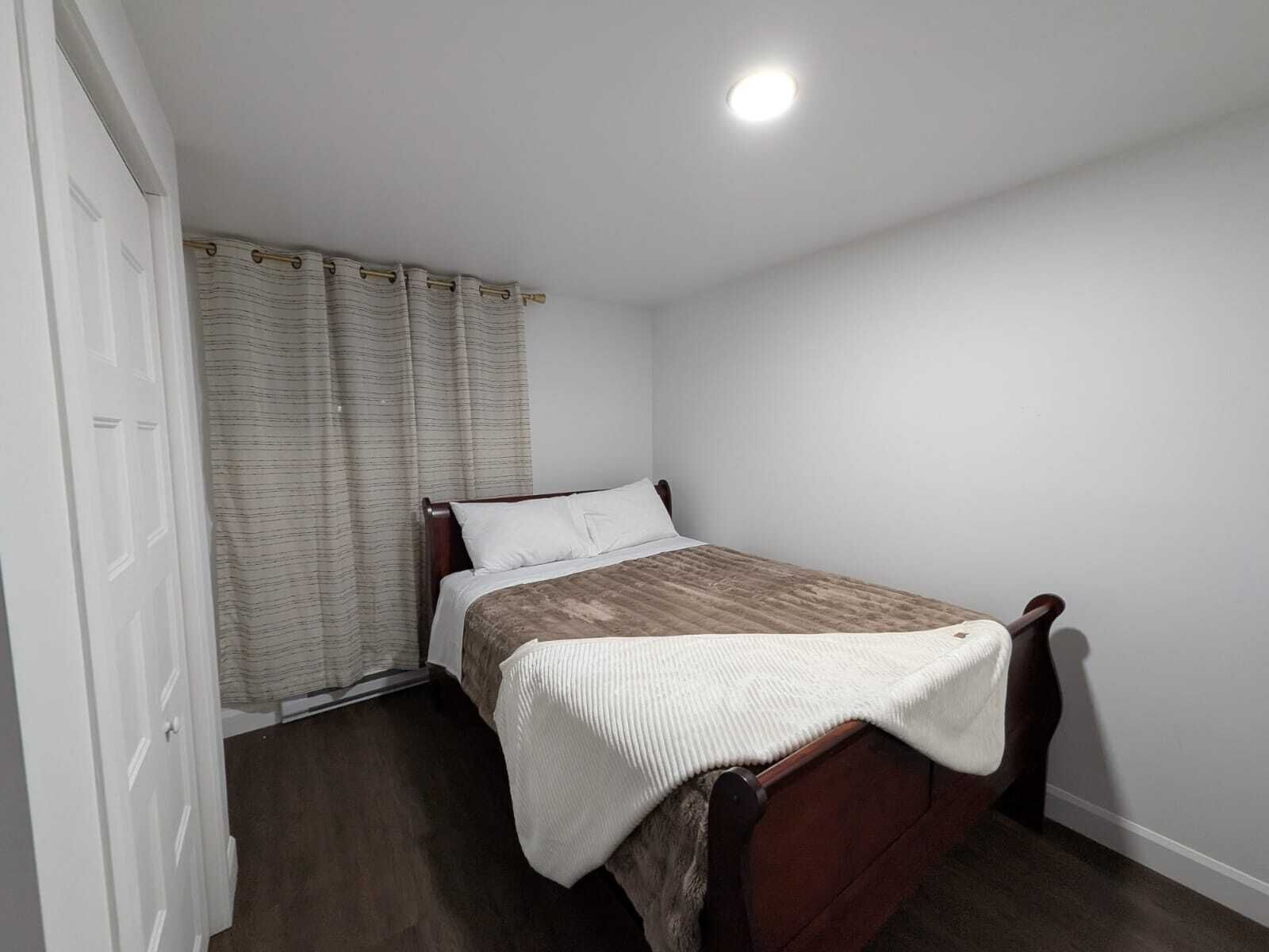 A bedroom with a single bed, a white door, and a curtain.