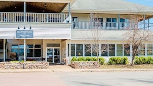 A two-story building with a balcony, a sign reading 'Bell Street Tavern,' and a stone wall in front. - Bell Street Lodging-Suite (La Pointe)