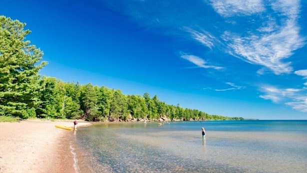 A beach with clear water, trees, and a clear sky. - Bell Street Lodging-Suite (La Pointe)